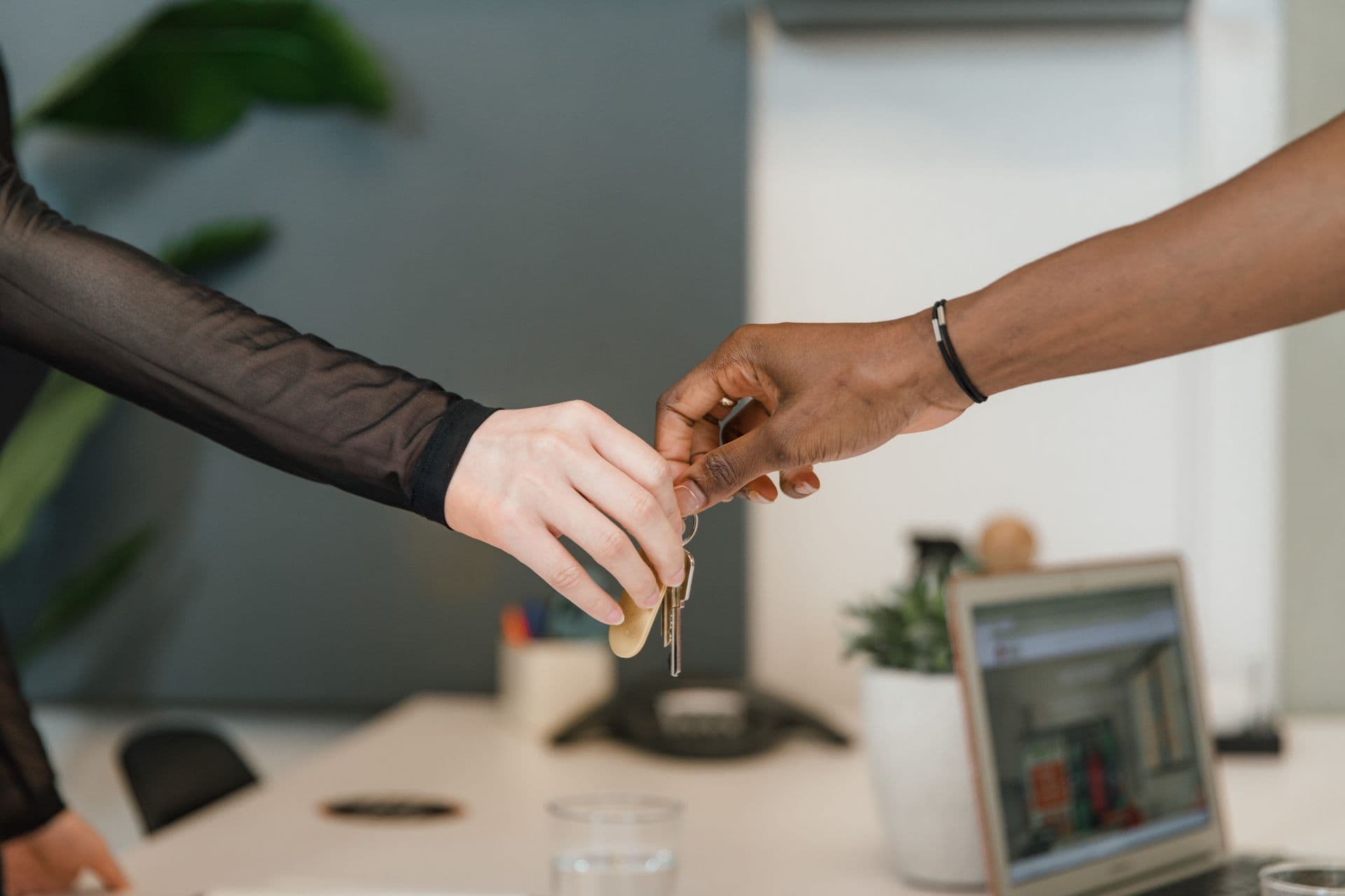Car keys passing from one hand to another over a desk