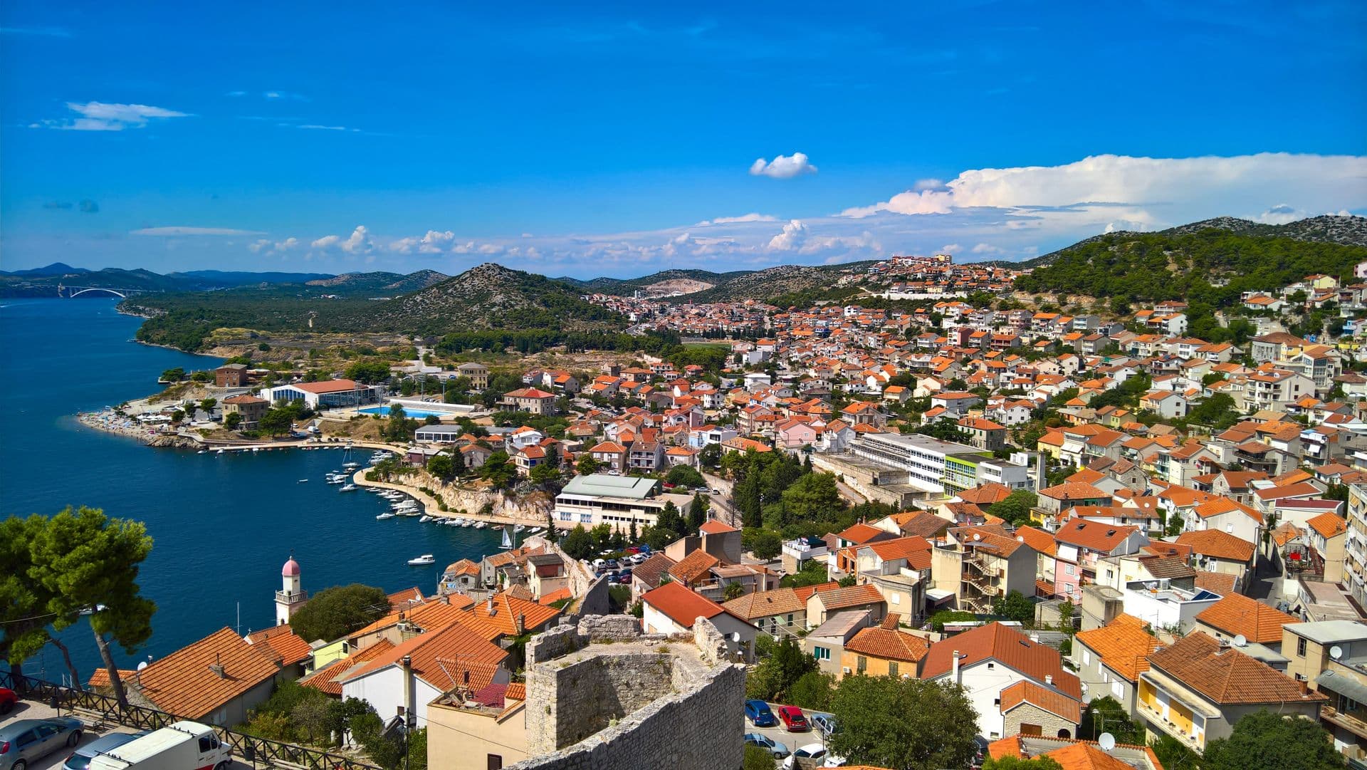 Sibenik's red roofs spilling down to the channel, from above