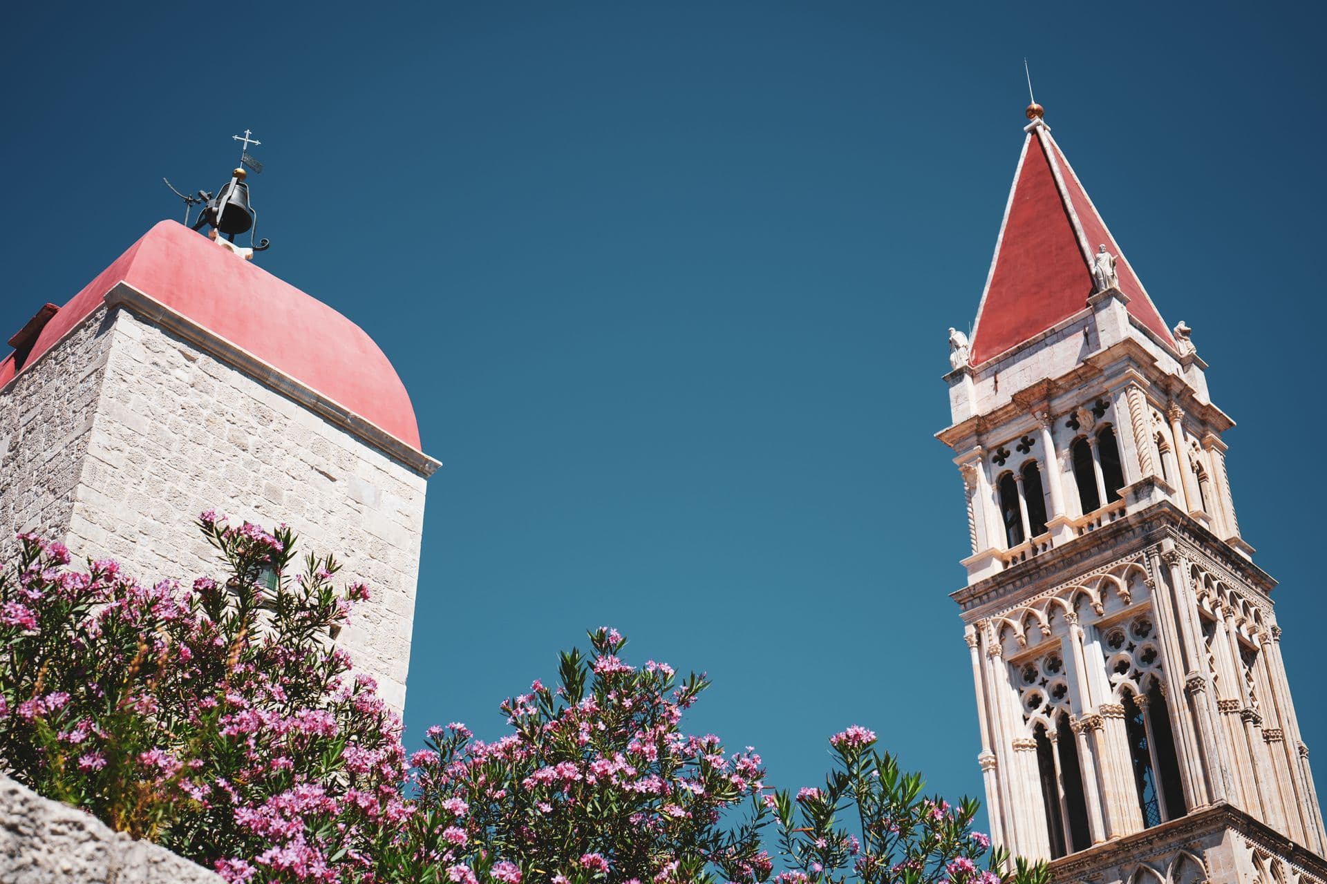 Trogir's cathedral bell tower and a stone campanile against a blue sky
