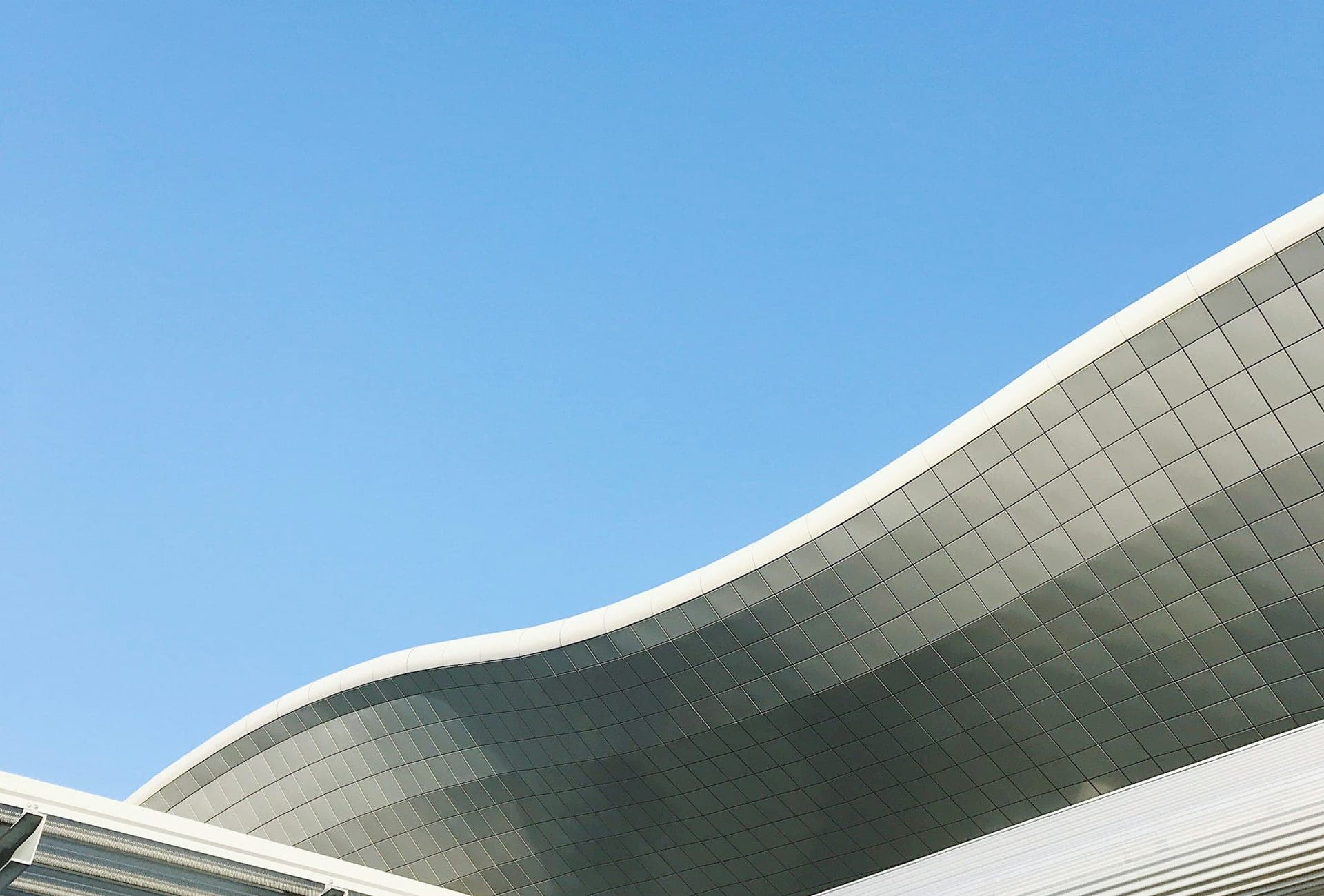 The curved metal roof of Zagreb Airport's Franjo Tudman terminal against a clear blue sky